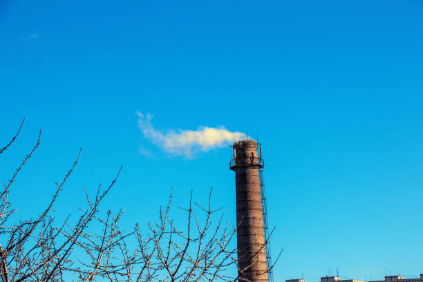 White-yellow smoke from the chimney of the boiler room against the blue sky. Ecology concept. Energy crisis. stock photo