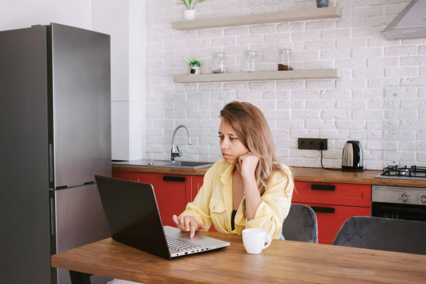 istock A young woman working on a laptop from home and drinking coffee or tee. Freelance 1400482320