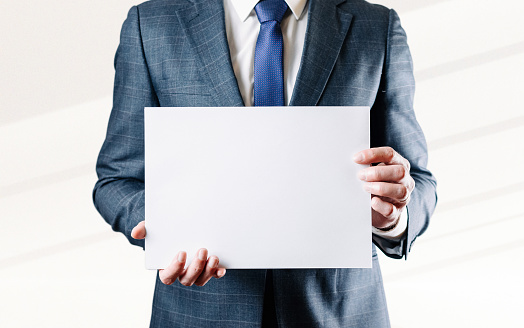 Businessman blank card. White blank board template holding business man on white background. Copy space empty poster