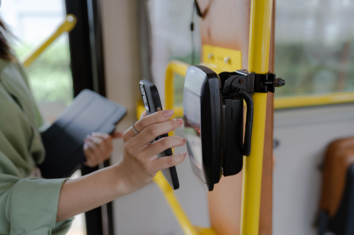 Freelancer asian woman using travel card to pay for public bus ride  while on the way to work