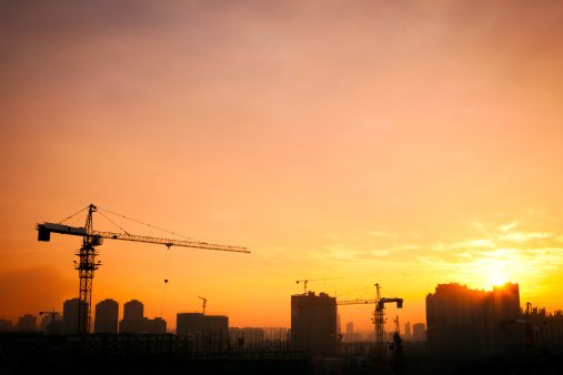 Silhouette of the tower crane on the construction site with city building background