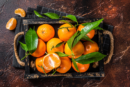 Fresh mandarin oranges or tangerines fruits with leaves. Dark background. Top view.