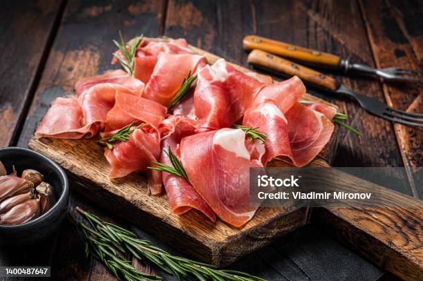 Slices Of Jamon Serrano Ham Or Prosciutto Crudo Parma On Wooden Board With Rosemary Wooden Background Top View Stock Photo - Download Image Now