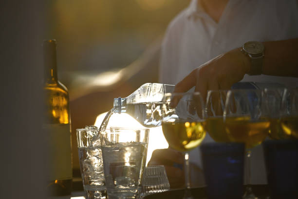 istock Waiter pouring water into glasses 1400488265