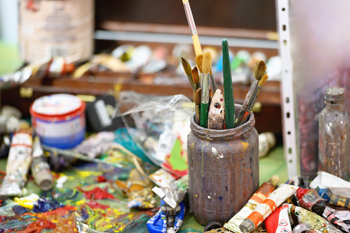 Busy studio of a painter, messy brushes and paint all over the studio, Nikon Z7