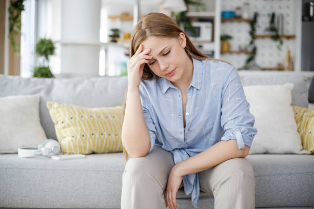 istock Woman with headache sitting on the couch 1400489639