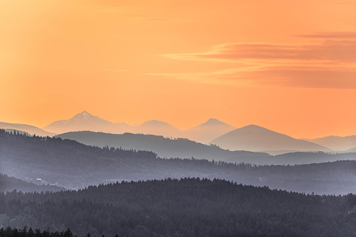 Sunset over rolling hills on Vancouver Island with rocky mountains in background