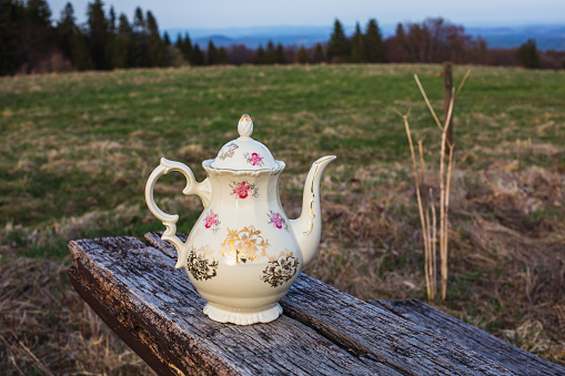 old antique teapot outside on rustic wooden table in nature