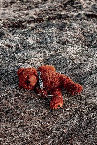 istock brown teddy bear lying abandoned on the floor outside 1400491917