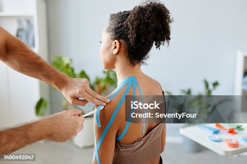 istock Therapist Putting Physio Tape on Young Woman 1400492047