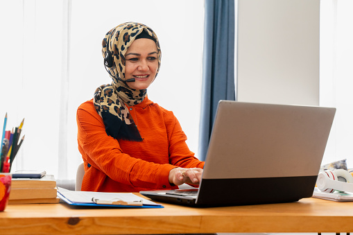 Muslim woman working. Pretty woman wearing hijab in front of laptop search and doing office work, business, finance and workstation concept.  Arabic woman working on laptop on startup project, copy space