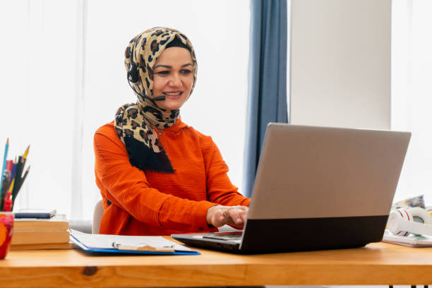 woman wear headset looks at laptop talk by videocall stock photo