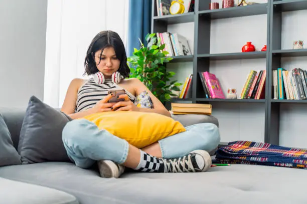 Photo of teen girl checking social media holding smartphone at home