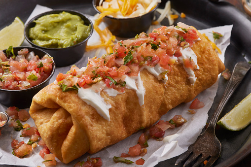 Chicken Chimichanga. A Deep Fried Chicken Burrito with Refried Beans, Mexican Rice, Cheese and Onions with guacamole, Pico de gallo and Sour Cream