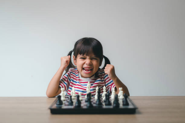 niña asiática jugando al ajedrez en casa.una partida de ajedrez - concentration chess playing playful fotografías e imágenes de stock