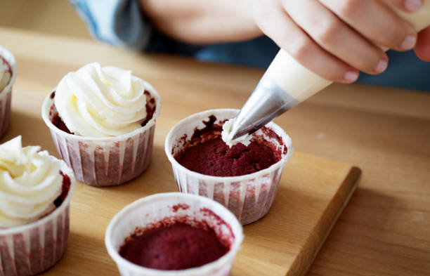 istock A young woman decorates muffins with white cream in her kitchen. 1400497403