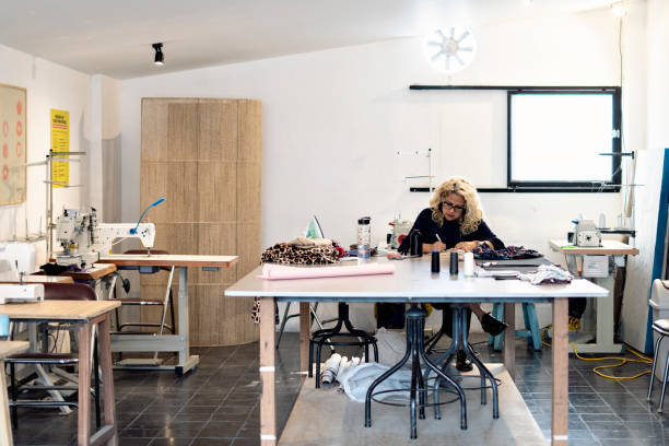 istock Woman seamstress sitting in her workshop while writing in a notebook on the table. 1400498535