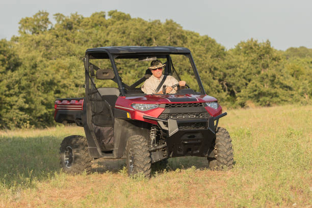 Man driving a UTV A man is driving his red UTV on his ranch in Texas side by side stock pictures, royalty-free photos & images