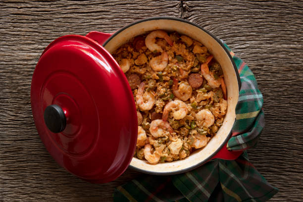 jambalaya in un coccio da forno olandese su uno sfondo di legno rustico - jambalaya foto e immagini stock