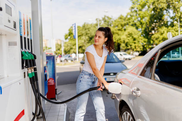 燃料ポンプでガスタンクに燃料を補給する動揺した女性 - gas prices energy crisis environment finance ストックフォトと画像