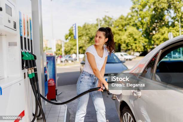 Upset Woman Refueling The Gas Tank At Fuel Pump Stock Photo - Download Image Now - Gasoline, Gas Station, Fuel Pump
