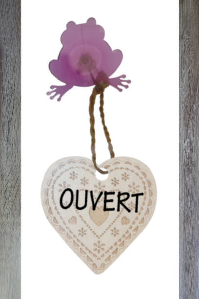 Open sign suspended and attached to a store window by a frog-shaped suction cup   Window decoration  Message written in French