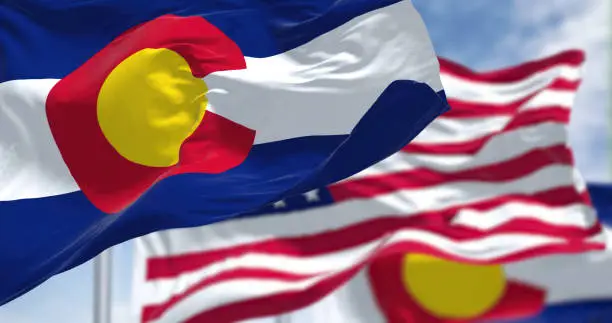 Photo of Colorado state flags waving along with the national flag of the United States of America