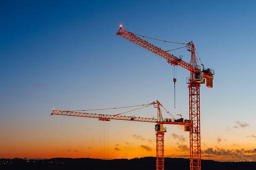 building cranes on the construction site at sunset background