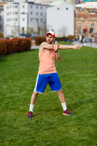 A Handsome Young Man is Enjoying an Exercise while Stretching on in a Grass Field.