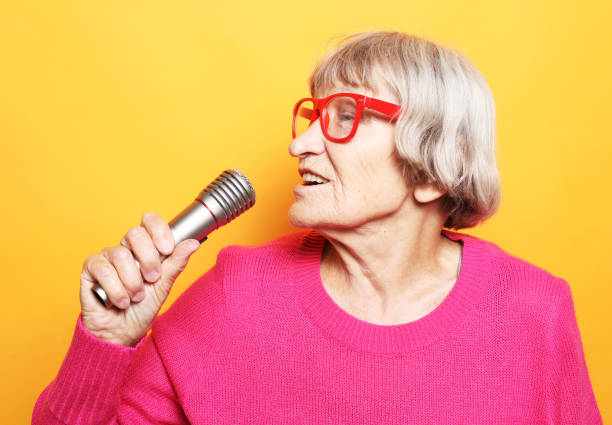 istock Happy old woman singing with microphone over yellow color background 1400518939
