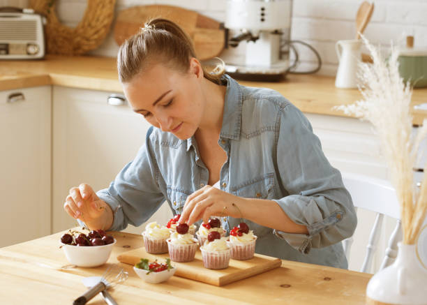 istock Young woman pastry chef decorates cupcakes with berries 1400522565