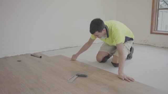 Man installing new timber laminated wooden floor, home improvement, house renovation project concept
