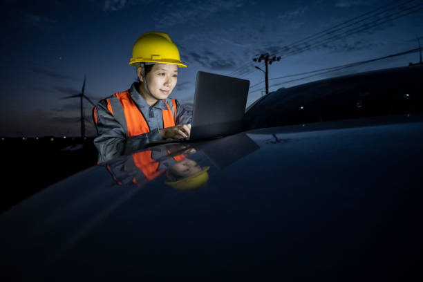 istock An Asian female engineer works on a laptop at a seaside wind farm. 1400528832
