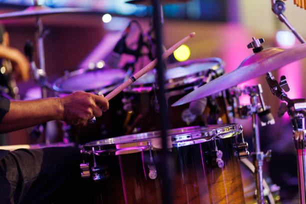 Cropped image of a musician playing drum set on the stage. Close up hands of a musician playing drum set in a concert. Motion image. live event stock pictures, royalty-free photos & images