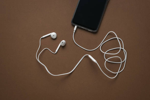 istock White headphones with a wire connected to a black smartphone. 1400528986