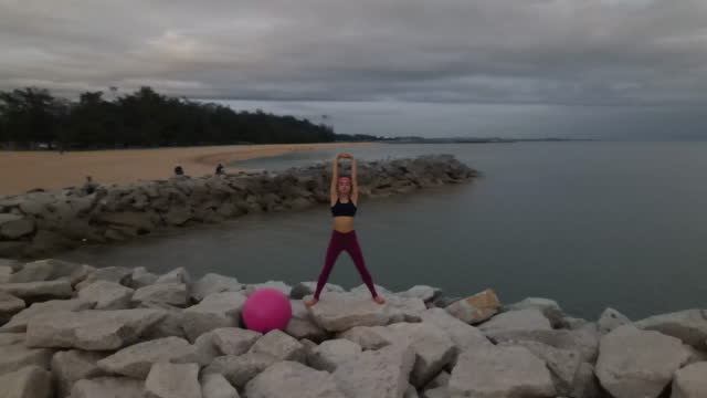 Woman exercising and meditating yoga exercise outdoors by the sea .
