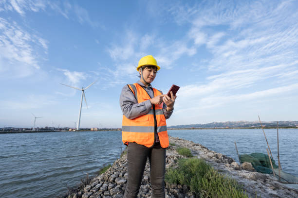 istock A female engineer uses her mobile phone at a wind farm by the sea. 1400529130