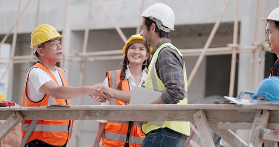 Civil engineer or architect hand shake greeting with contractor or partnership who work together on housing project. Have discussing about building styles and inspect progress of  at construction site