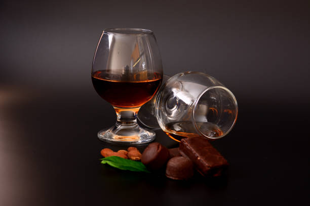 istock Two glasses of cognac, chocolates, nuts and mint leaves on a black background. 1400530780