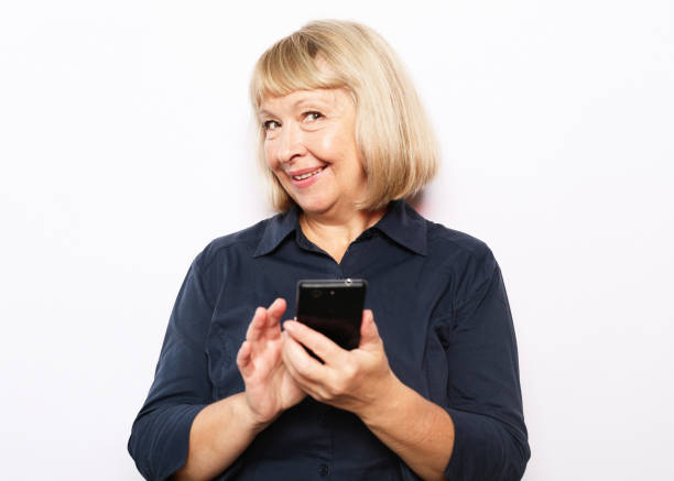 istock Attractive elderly woman with smartphone over white backgrou 1400531611