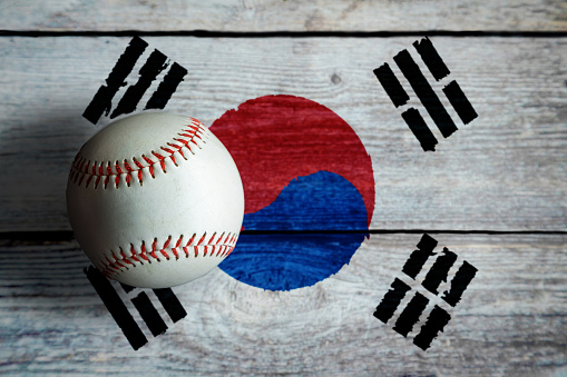 Leather baseball on rustic wooden background painted with South Korean flag with copy space. South Korea is one of the top baseball nations in the world.