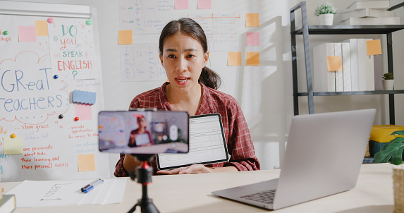 Young Asian woman teacher teaching online lesson class on video call via smartphone at home.