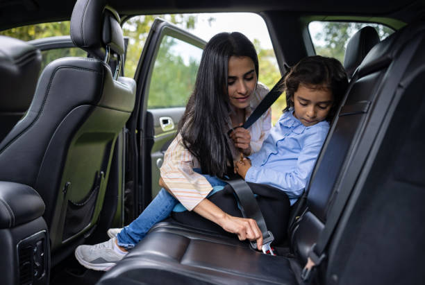 mother buckling the seat belt of her daughter - fastening imagens e fotografias de stock