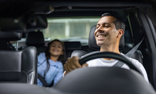 Happy Latin American father driving with his daughter in the car  and smiling - lifestyle concepts