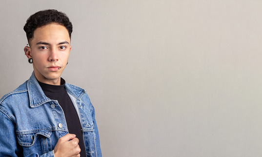 Brazilian young man with confident pose, wearing black turtleneck shirt and a denim jacket.
