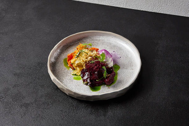 istock Baked root vegetables in handmade ceramic dishware. Vegan food - caramelized carrot, beetroot and celery on modern crockery. Vegetarian food innovative recipes 1400536258