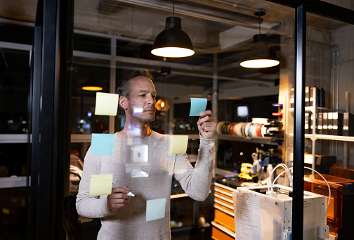Latin American business man working late at the office and organizing ideas using post its