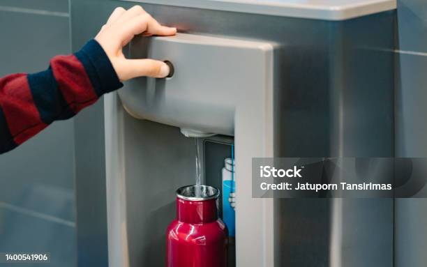 Close Up Of Hand Pressing Button Of Drinking Water Filling Station At The Airport Stock Photo - Download Image Now