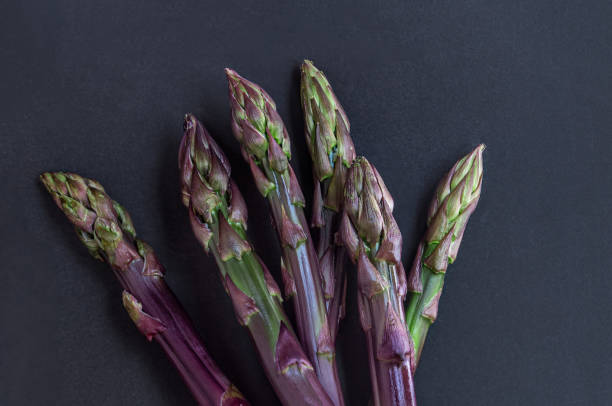 istock Asparagus. Fresh purple asparagus on black slate background. Top view 