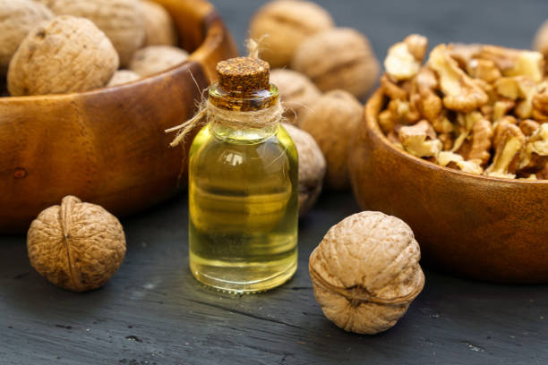 istock Glass bottle with essence, raw walnut peeled and in their shells, rustic style, selective focus 1400549122